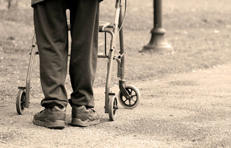 Bildet viser en eldre mann som går med gåstol.