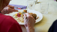 Bildet viser en eldre mann eller kvinne som spiser middag