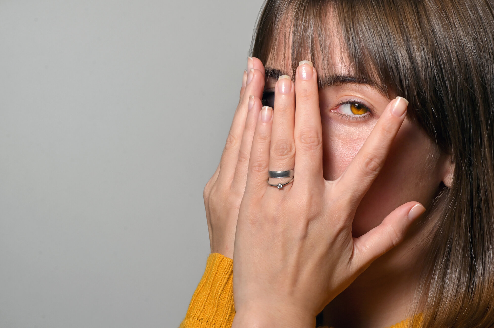 Bildet viser en kvinne med hendene foran øynen, men som titter mellom to fingre