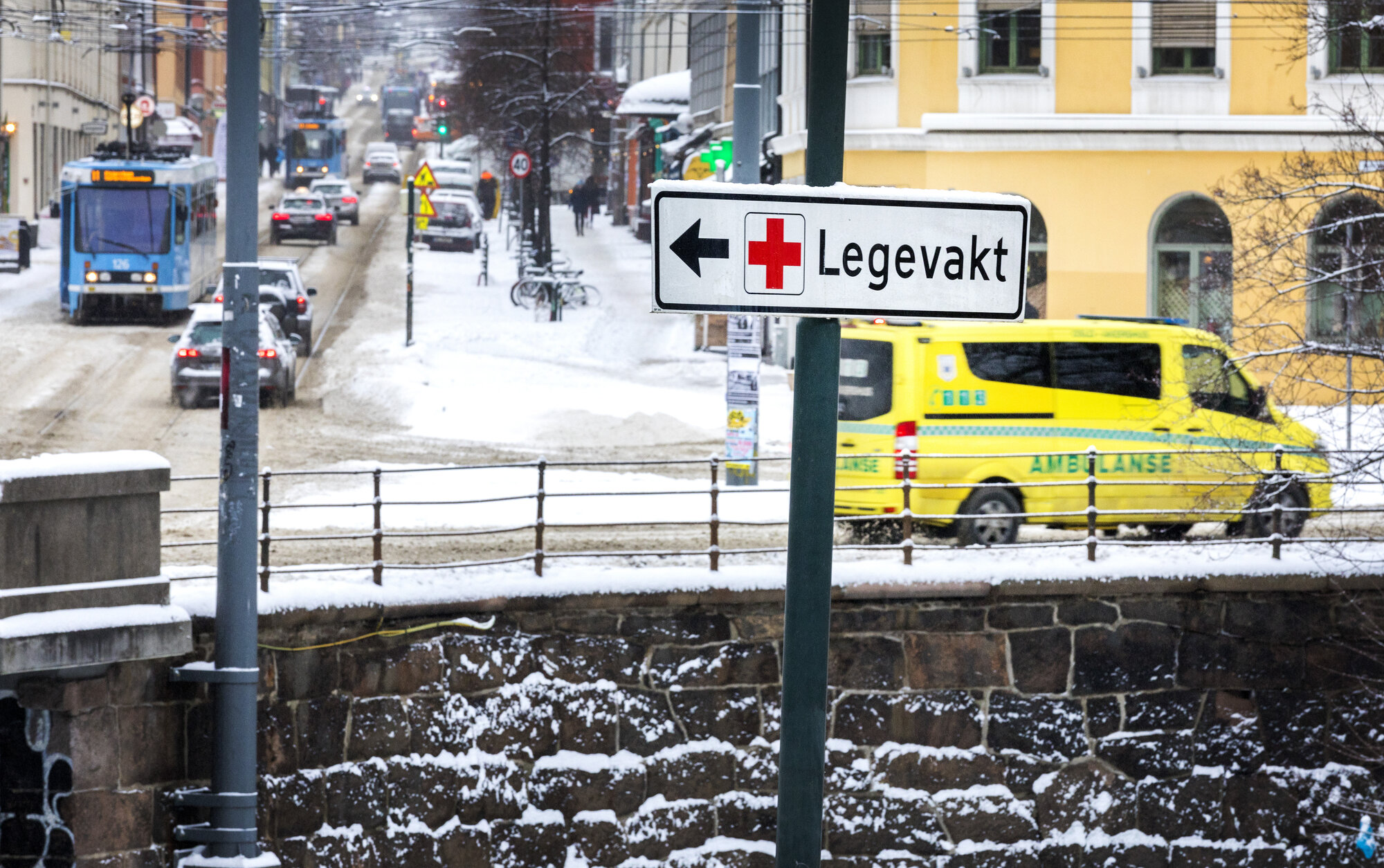 Bildet viser trafikkbildet i Oslo. Et skilt peker til Legevakta, mens en ambulanse kjører forbi