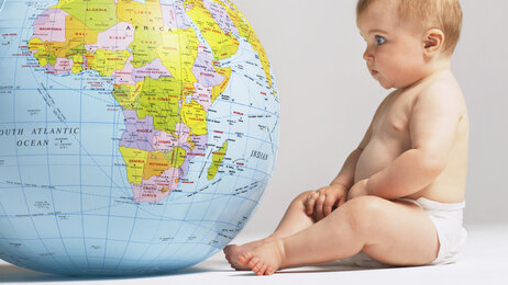 Bilde av en baby som titter på en globus