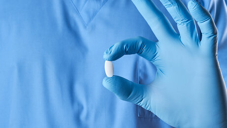 Bildet viser en sykepleier som holder rundt en pille. 
