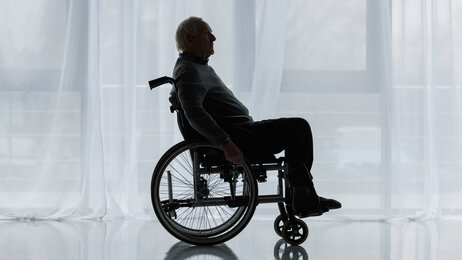 Bildet viser en eldre mann som sitter i rullestol