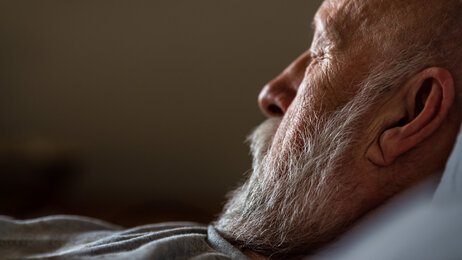 Bildet viser en eldre mann i profil med lukkede øyne. Han ligger i sengen.