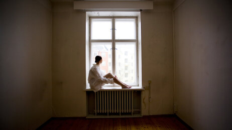 Bildet viser en kvinne som sitter alene i et vindu.