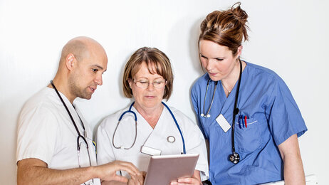 Bilde viser tre helsearbeidere som studere innhold på en Ipad.