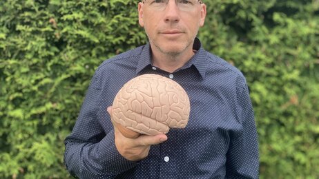 Bildet viser Tommy Skar som viser frem en plastmodell av en hjerne