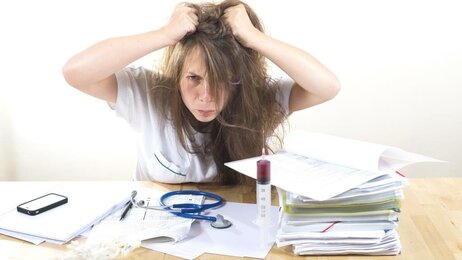 Bildet viser en frustrert sykepleier som river seg i håret.
