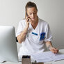 Bildet viser en ung, kvinnelig sykepleier som snakker i telefonen og tar notater.