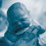 Bildet viser en nyfødt baby som holdes av et par hender