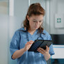 Bildet viser en sykepleier som skriver på et nettbrett.