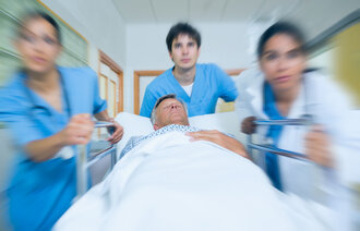 Helsepersonell løper med pasient i sykehusseng.