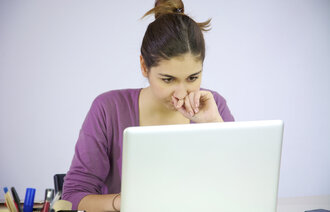 Bildet viser en kvinne som sitter ved en datamaskin.