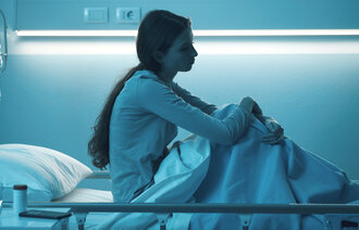 Ung, melankolsk kvinne i en sykehusseng