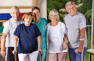 Bildet viser fire eldre personer som står sammen med en sykepleier. To av dem har krykker.
