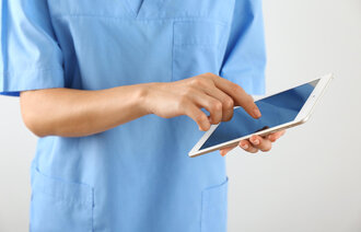 Bildet viser en sykepleier som skriver på en Ipad