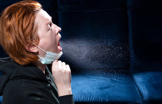 Bildet viser en kvinne som hoster, og dråper av virus former en sky rundt henne