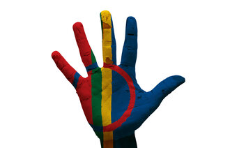 Bildet viser en menneskehånd påmalt det samiske flagget.