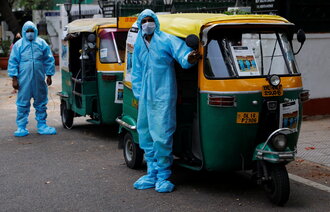 Bildet viser to rickshaw-ambulanser med to sjåfører ikledd smittevernutstyr.