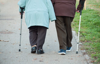 Et eldre par med spaserstokk går tur
