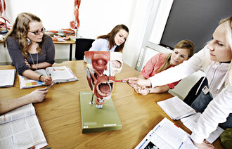 Bildet viser en gruppe studenter som sitter rundt en anatomisk modell