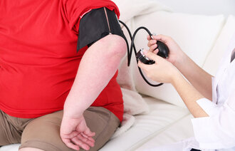Bildet viser en sykepleier som måler blodtrykket på en mann med fedme