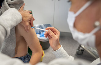 Bildet viser en sykepleier som setter koronavaksine i armen på et barn.