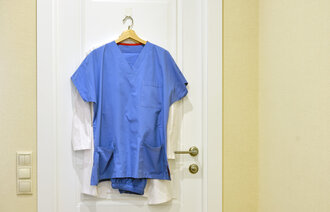 Bildet viser en sykepleieruniform som henger på en dør.