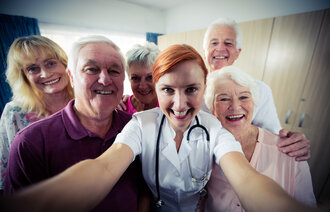 Bildet viser en sykepleier som tar en selfie sammen med flere mennesker