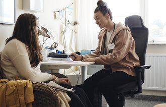 Bildet viser en helsesykepleier som prater med en elev på et kontor