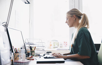 Bildet viser en ung kvinnelige sykepleier som jobber foran en datamaskin