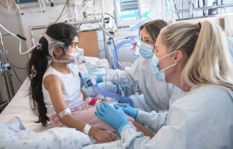 Bildet viser en ung pasient med to sykepleiere.