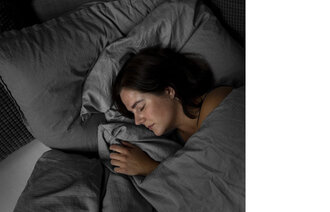 Bildet viser en kvinne som sover i en seng