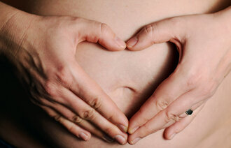 Gravid kvinne viser frem magen sin. 