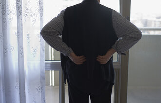 Bildet viser en eldre mann som står med ryggen til