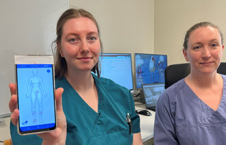 Bildet viser to sykepleiere som viser frem en mobilapp.