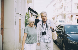Bildet viser et eldre par som går i en by