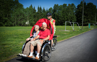 Bildet viser enhetsleder Håvard Lobben-Seth som sykler pasient Solveig Johansen og samboer Alf Krossli på besøk ved Gulset sykehjem i Skien.