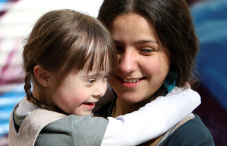 Bildet viser en lykkelig mor som holder en glad datter, som har Downs syndrom