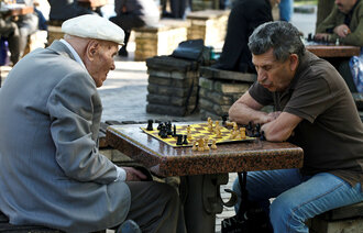 Bildet viser to eldre herrer som spille sjakk i en park