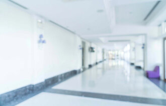 Uklart foto av hvit sykehuskorridor.