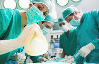 Sykepleiere og leger som er på en operasjonsstue og klargjør en pasient til narkose.