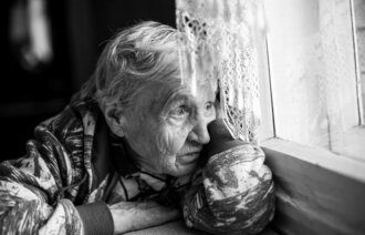 Bildet viser eldre kvinne som ser ut av induet