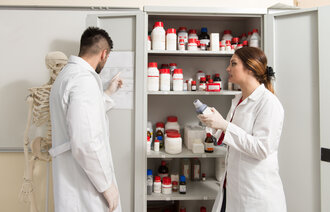 Bilde av to medisinstudenter som kikker inn i et medisinskap