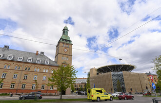 Gamle bygninger med helikopterlandingsplass fra Ullevål sykehus. Ambulanse og biler i forgrunnen.  