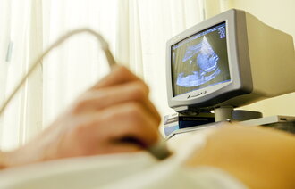 Bildet viser en gravid mage som undersøkes med ultralyd.