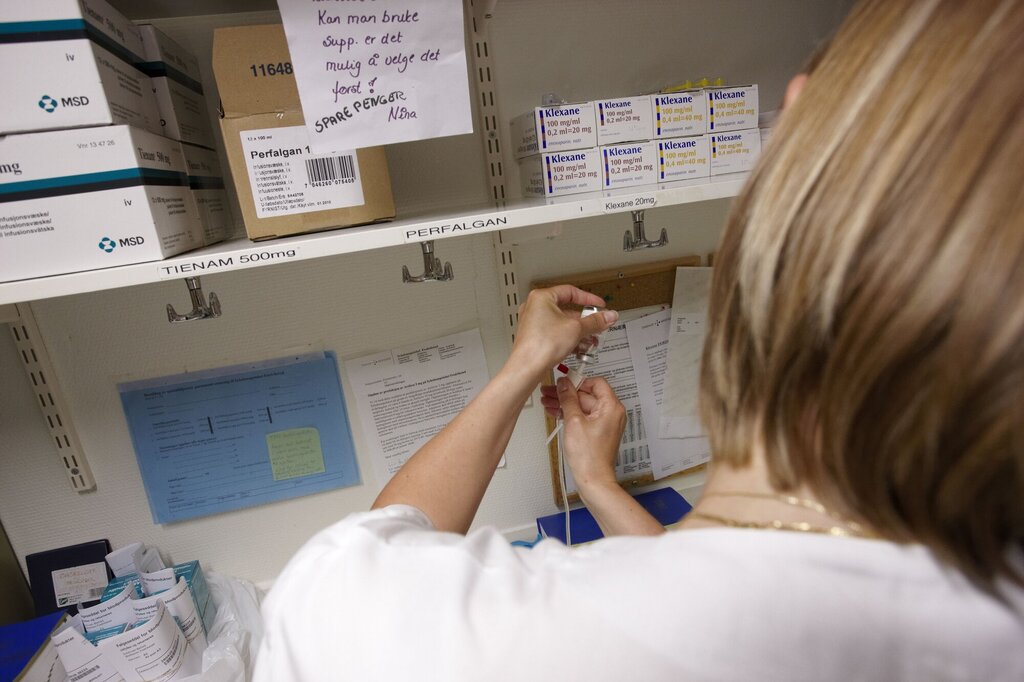 Bildet viser en sykepleier på et medisinrom som trekker opp en sprøyte.