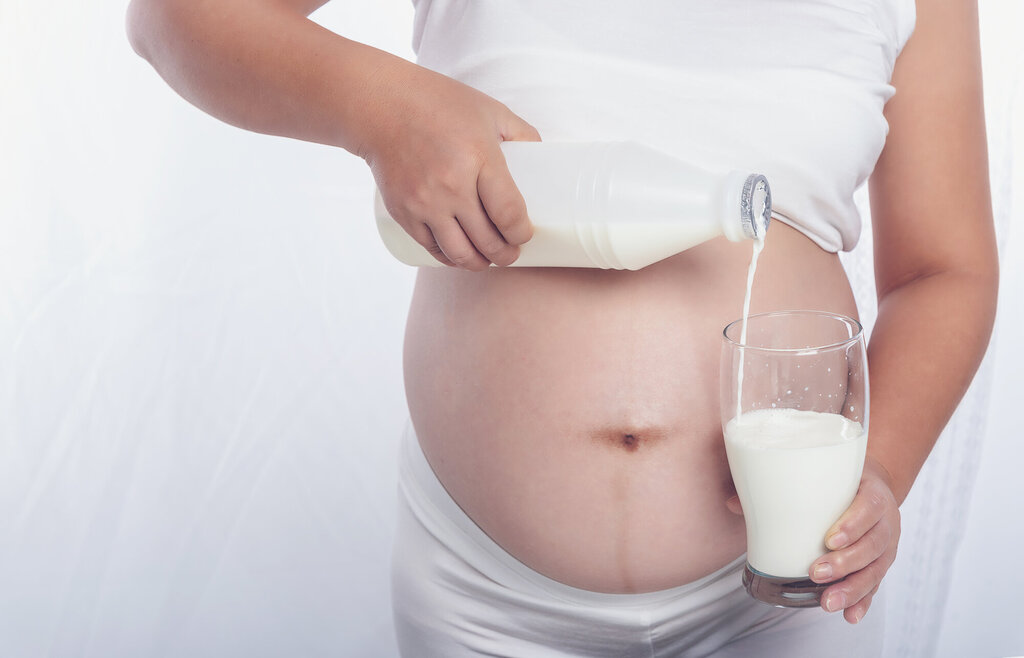 Bildet viser en gravid kvinne som skjenker seg et glass melk.