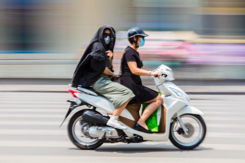 Bildet viser to på scooter som bruker munnbind.