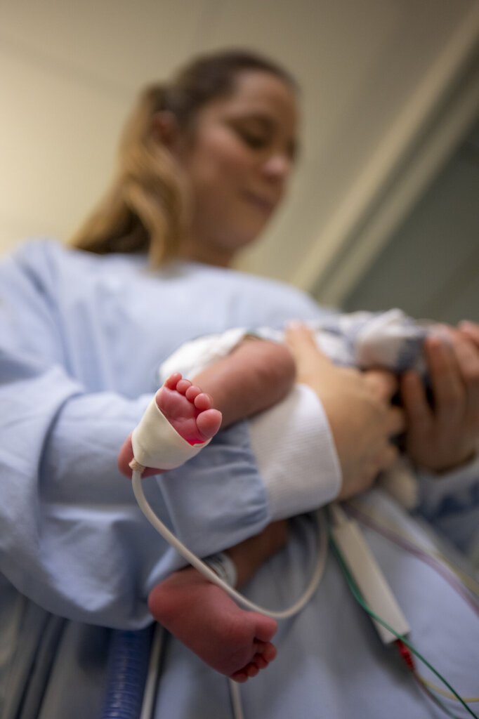 Bildet viser Julie Dahle som holder en liten baby, med oksygenmetningsmåler på foten.